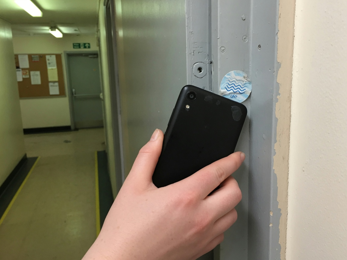 Handy am Türrahmen, NFC-Stempelung